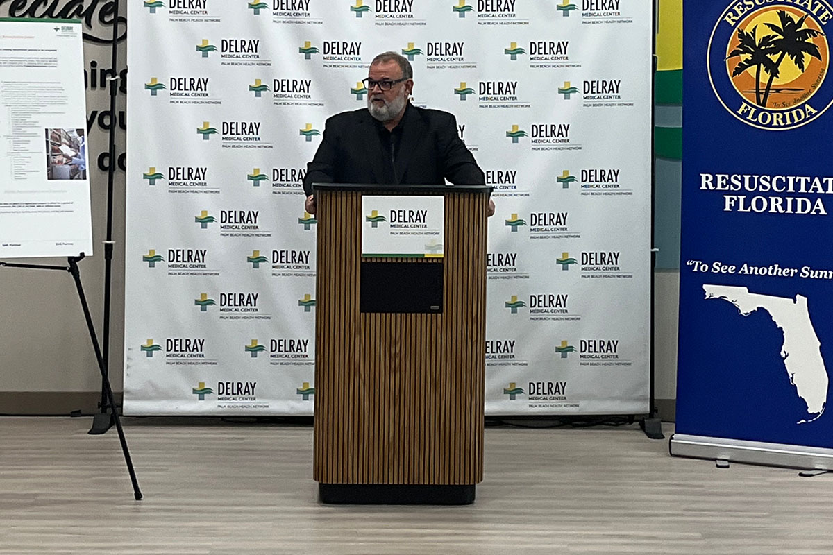 A man in a black suit at a podium giving a speech