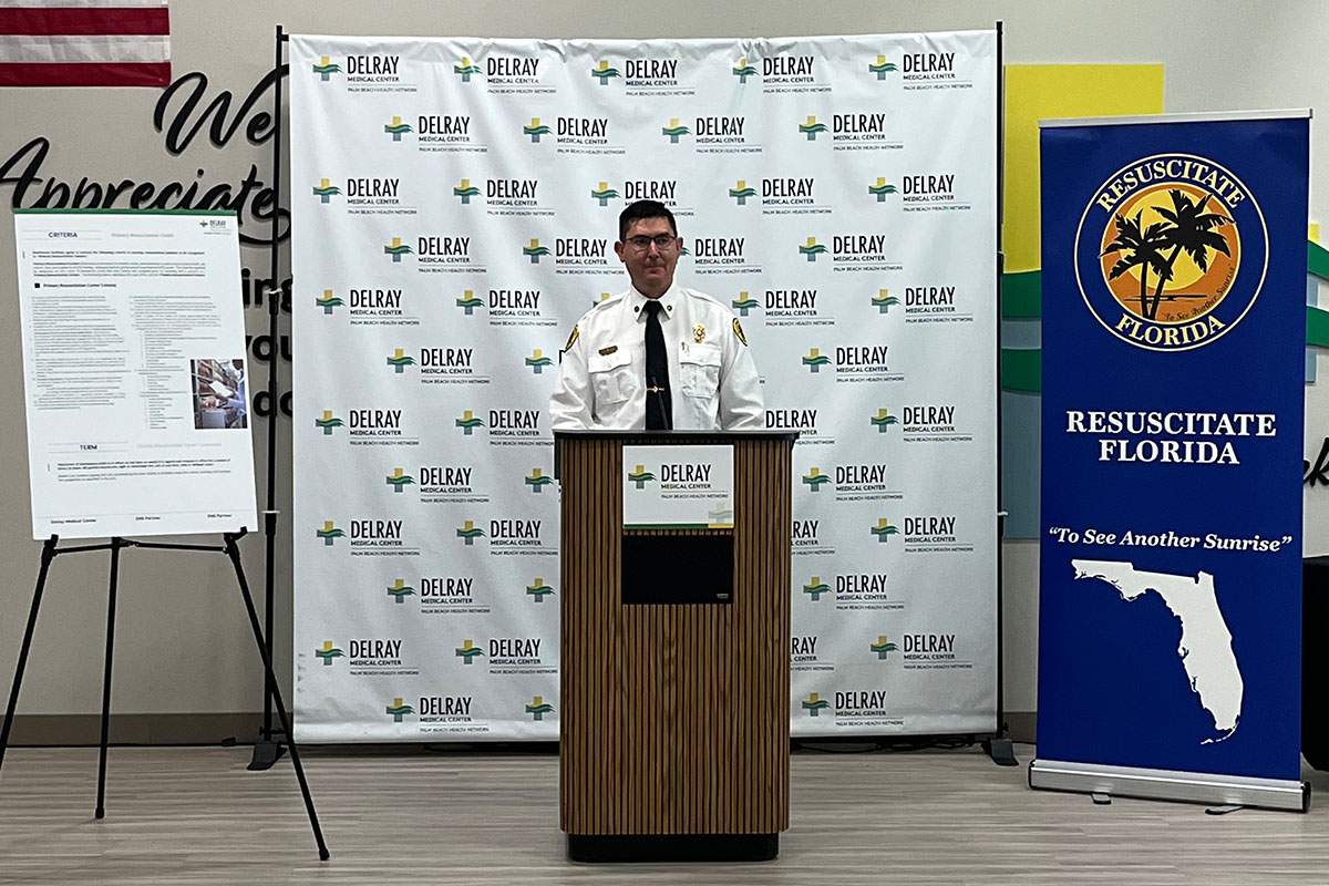 A man in a white shirt and black tie giving a speech at a podium